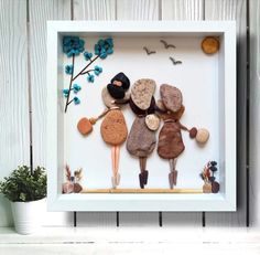 an image of three people made out of rocks in a shadow box with blue flowers