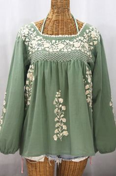 "* Ornate hand embroidery and smocking with hand crocheted trim on the neck and long gathered sleeves, available here in SAGE GREEN with CREAM embroidery. * Light, gauzy and semi-sheer 100% cotton throughout. * Dyed, distressed and embroidered by hand for an authentic, retro-vintage and boho-chic hippie vibe. * Our colorful and ornate floral embroidery patterns are a faithful tribute to the traditional hippie peasant Mexican blouses of the 1970's. * Each top is like a one-of-a-kind work of art. Mexican Blouses, Long Sleeve Style, Embroidery Light, White Peasant Top, Cream Embroidery, Mexican Blouse, Floral Embroidery Patterns, Embroidered Sleeves, Gathered Sleeves