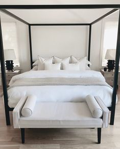 a four poster bed with white linens and pillows