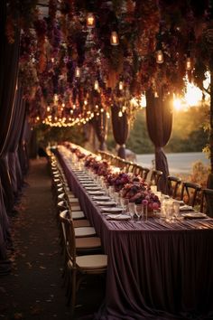 a long table is set up with purple flowers and candles for an outdoor wedding reception