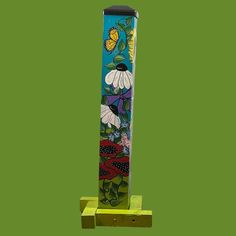 a tall glass vase with flowers painted on it's sides, sitting on a wooden stand