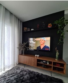 a flat screen tv sitting on top of a wooden entertainment center next to a window