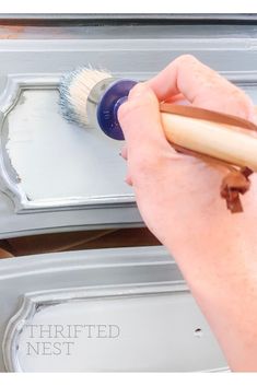 someone using a brush to paint an old dresser