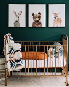 a baby's crib with three pictures hanging on the wall and an animal blanket