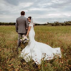 a bride and groom standing in the middle of a field