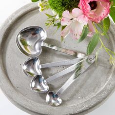 four spoons on a tray with flowers in the background