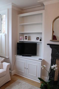 a living room filled with furniture and a flat screen tv on top of a white entertainment center