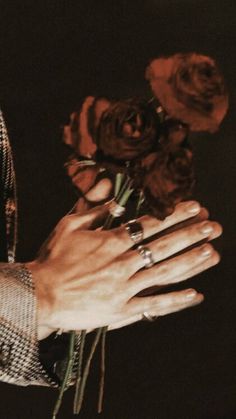 a person holding flowers in their hand with both hands on the other side of them