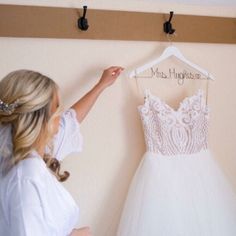 the bride is trying on her wedding dress in front of the hanger that says happily married