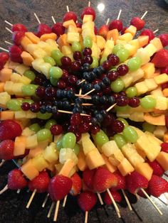 a fruit kabob with grapes, strawberries and pineapples arranged in the center