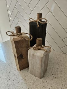 two wooden bottles tied with twine on top of a white countertop next to a black bottle