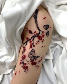 a woman's arm with red flowers and butterflies on it