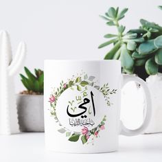 a white coffee mug sitting on top of a table next to succulents