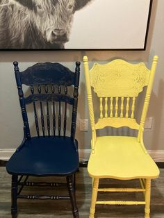 two chairs are painted yellow and blue in front of a cow print on the wall