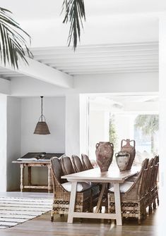 a dining room table with vases on top of it and chairs around the table