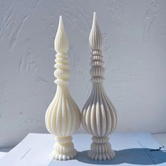 two white vases sitting next to each other on top of a paper covered table