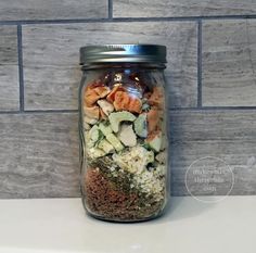 a glass jar filled with food sitting on top of a counter next to a tile wall