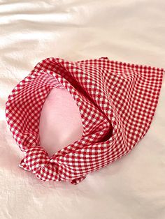 a red and white checkered scarf laying on top of a bed