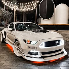 a white sports car parked in front of a building with christmas lights on the roof