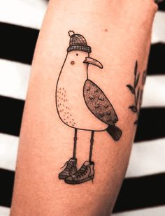 a bird with a hat on its head and boots is shown in this tattoo design