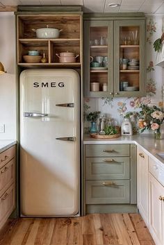 an old fashioned refrigerator in the middle of a kitchen with wooden flooring and cabinets