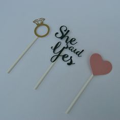 two cake toppers with the words she said yes and a ring on each one