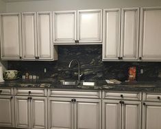 a kitchen with marble counter tops and white cabinets