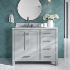 a bathroom vanity with a round mirror above it and white flowers in vases on the counter