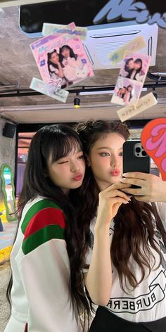 two young women taking a selfie in front of a mirror with stickers on it