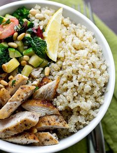 a white bowl filled with chicken, rice and vegetables on top of a green napkin