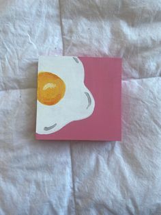 an egg painted on a pink and white canvas