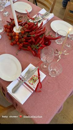 the table is set with red peppers and place settings