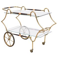 a glass and brass serving cart with wheels