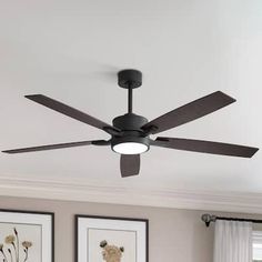 a ceiling fan in a living room with pictures on the wall