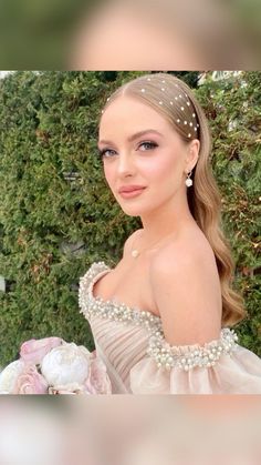 a woman in a dress with pearls on her head and flowers around her neck, posing for the camera