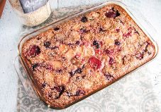 a casserole dish filled with fruit on top of a white and blue table cloth