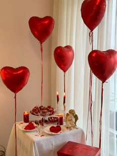 heart shaped balloons floating from the ceiling over a table