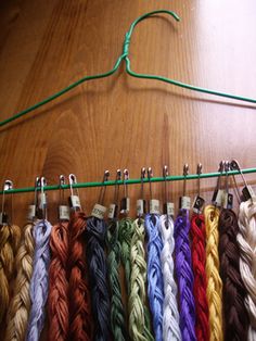 there are many different colors of yarn hanging on the clothesline with hooks and clips