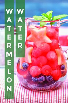 a pitcher filled with watermelon and blueberries on top of a striped table cloth