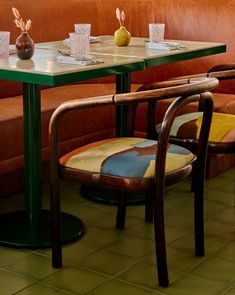 two chairs and a table in a room with orange walls, green flooring and brown leather couches