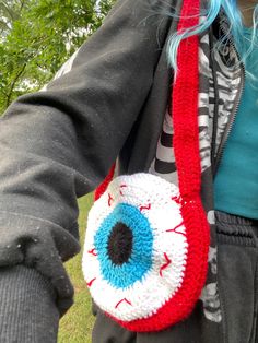 a woman with blue hair is holding an eyeball purse