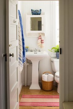 a white sink sitting next to a toilet in a bathroom under a window above a mirror