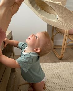 a little boy that is standing in front of a dresser with a hat on his head