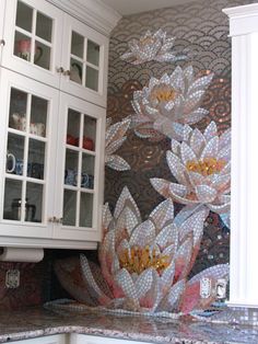 a kitchen with white cabinets and flowers painted on the backsplash wall behind it