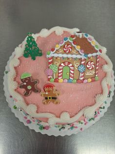 a decorated cake with gingerbread houses and candy canes on the icing is sitting on a table