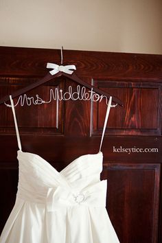 a wedding dress hanging on a wooden hanger