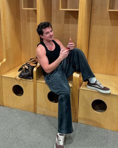 a man sitting on top of a wooden bench in front of closets with shoes