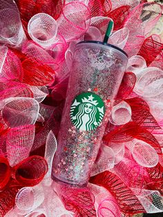 the starbucks cup is sitting on top of some pink netted mesh and it's full of sprinkles