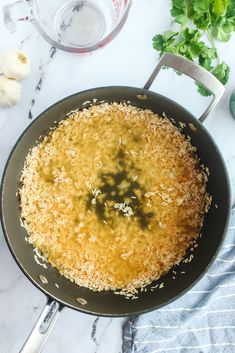 a frying pan filled with food on top of a counter next to garlic and parsley