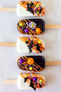 three halloween pops with candy and sprinkles on them